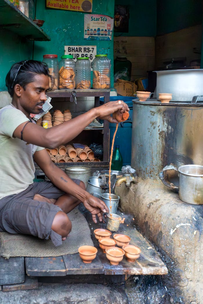 services-img Indian tea vendor pouring chai into clay cups in a street stall.