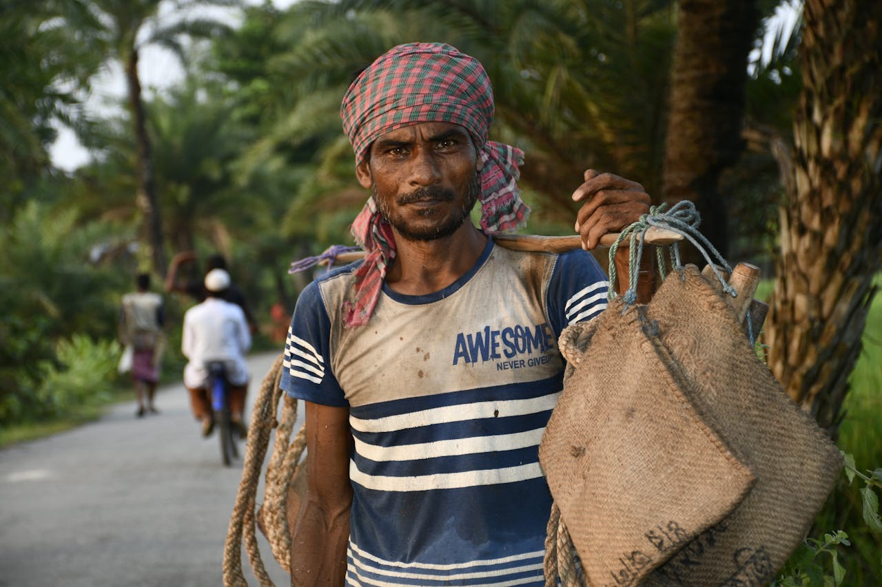 A rural worker in Bangladesh carrying jute bags along a village road in Pirganj.